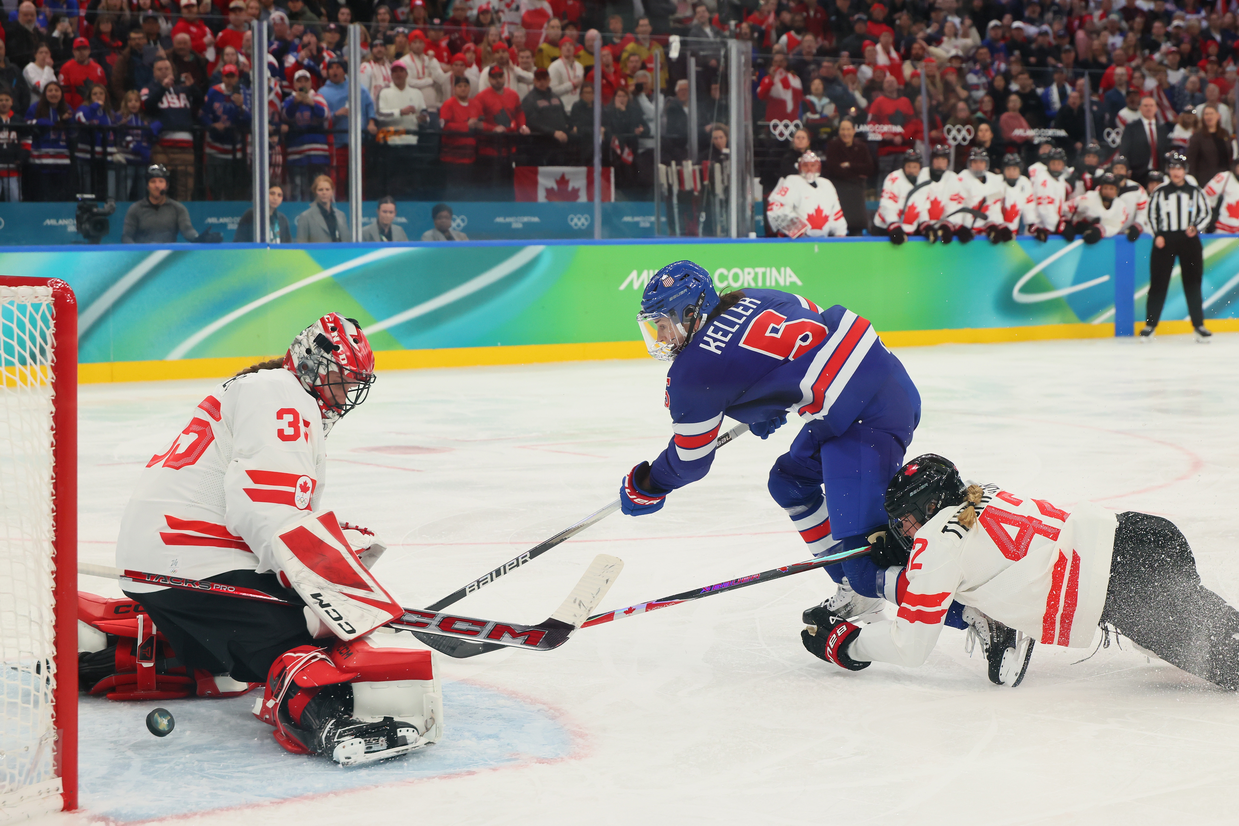 Hockey subordinate successful bluish avoids a diving hostile to people against a goalie successful achromatic and reddish during a match