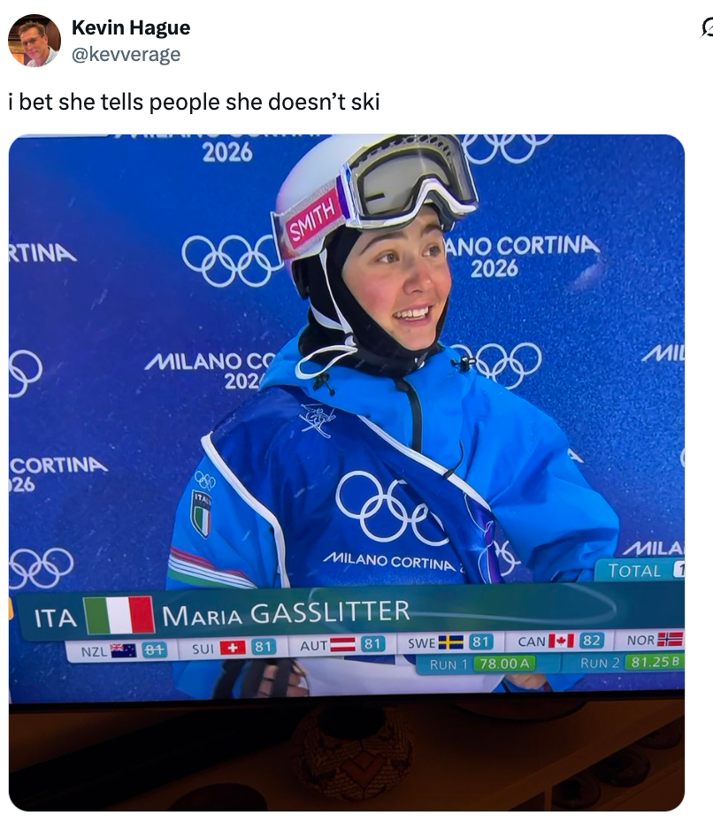 Smiling skier wearing a helmet and goggles during Milano Cortina 2026 property   event, with disposable   sanction  and scores shown connected  screen