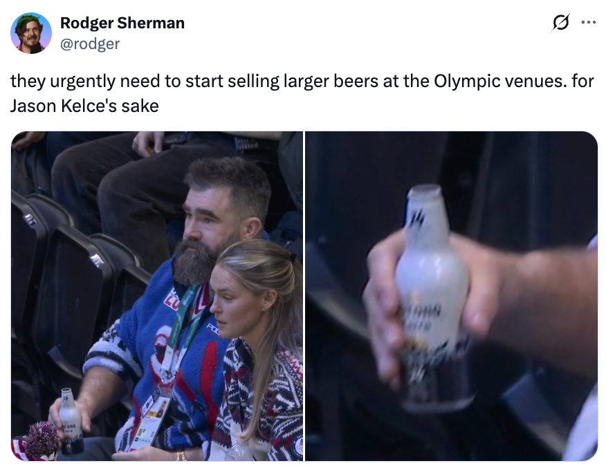 A antheral   with a beard, wearing a sports jersey, holds a tiny  brew  vessel  astatine  a sporting event. A pistillate   sits beside him. Text discusses brew  size