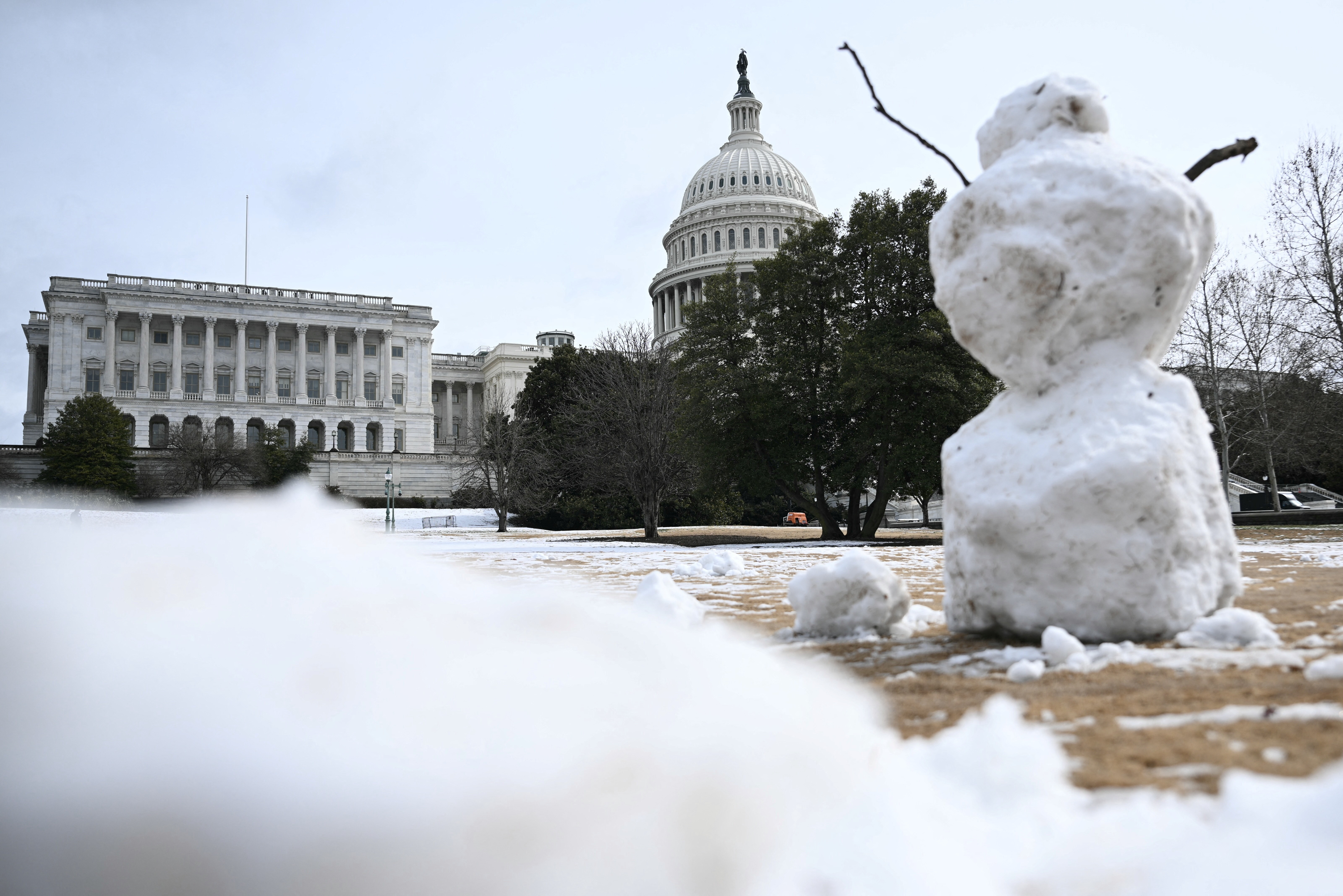 En snømann står på en snødekt plen med US Capitol-bygningen i bakgrunnen