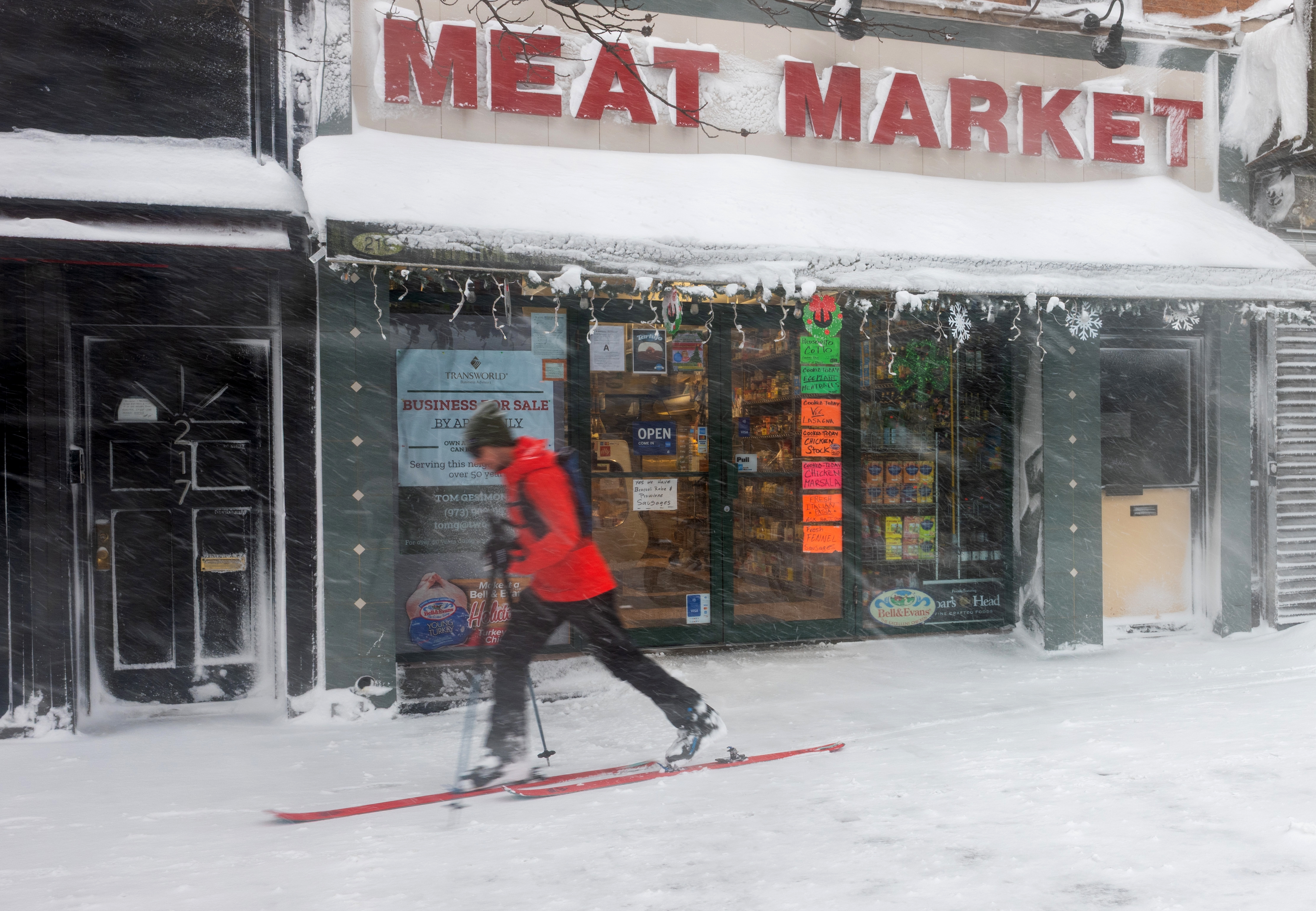Person som går på ski i en snødekt gate forbi en butikkfront merket
