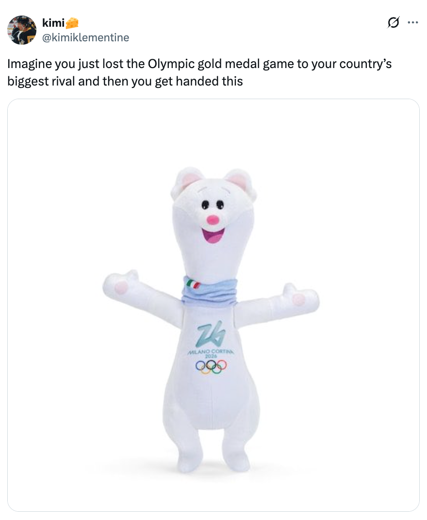 A plush carnivore  mascot from the Milan Cortina Olympics with a scarf, arms raised, and a playful expression