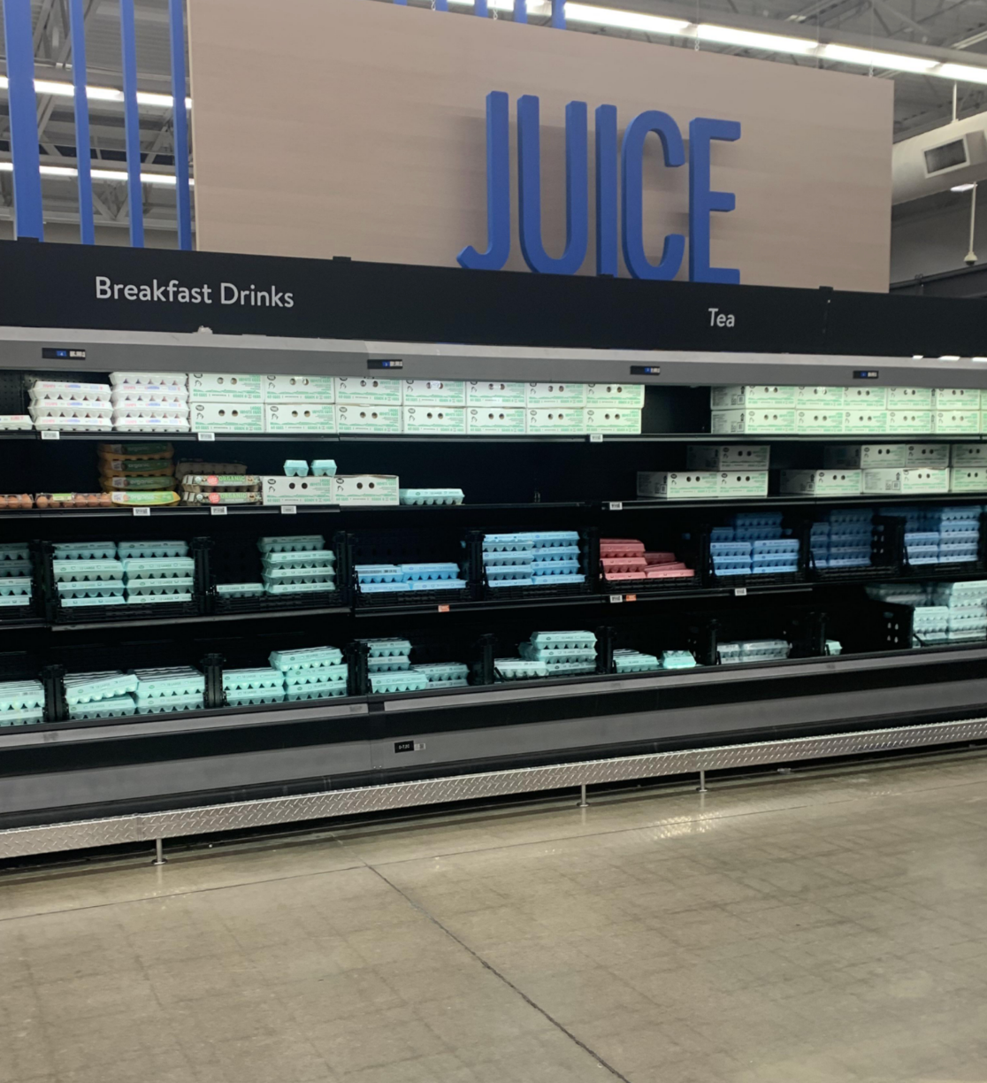 Egg cartons displayed under a sign meant for juice, breakfast drinks, and tea in a grocery store aisle
