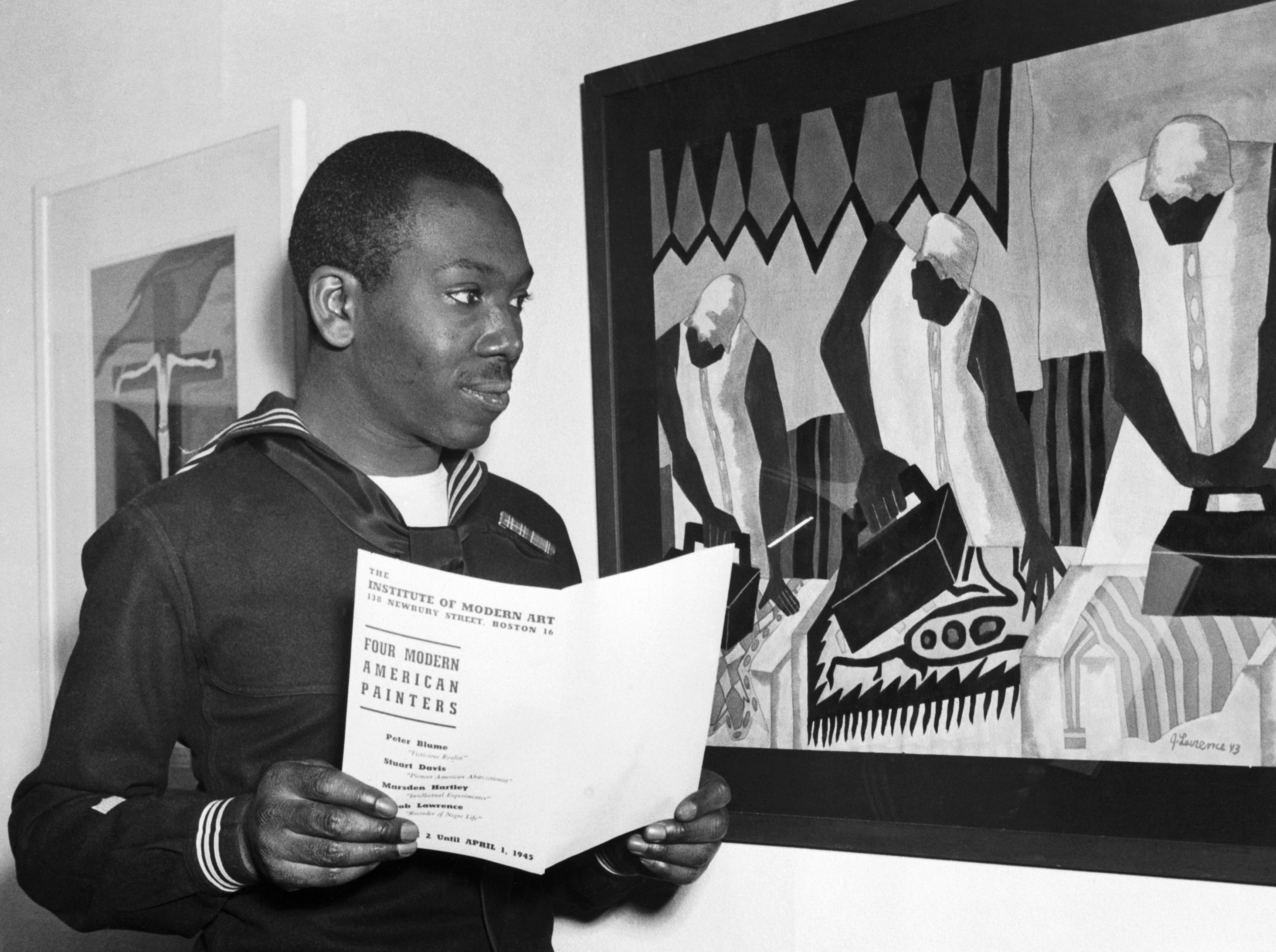 Person som undersøker kunstverk på et galleriarrangement. De holder en brosjyre med tittelen 