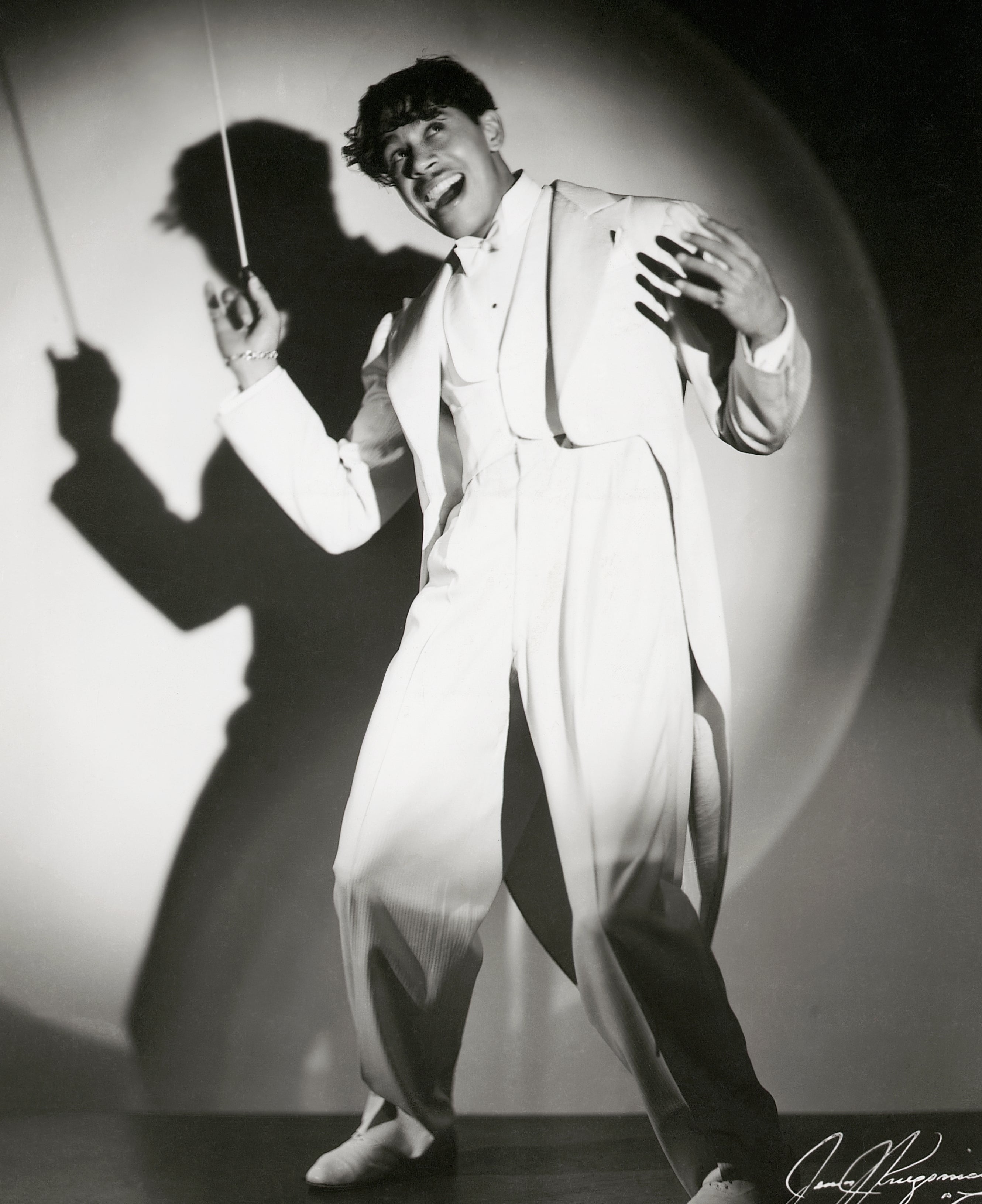 Person posing dramatically against spotlight, wearing a stylish, flowing suit