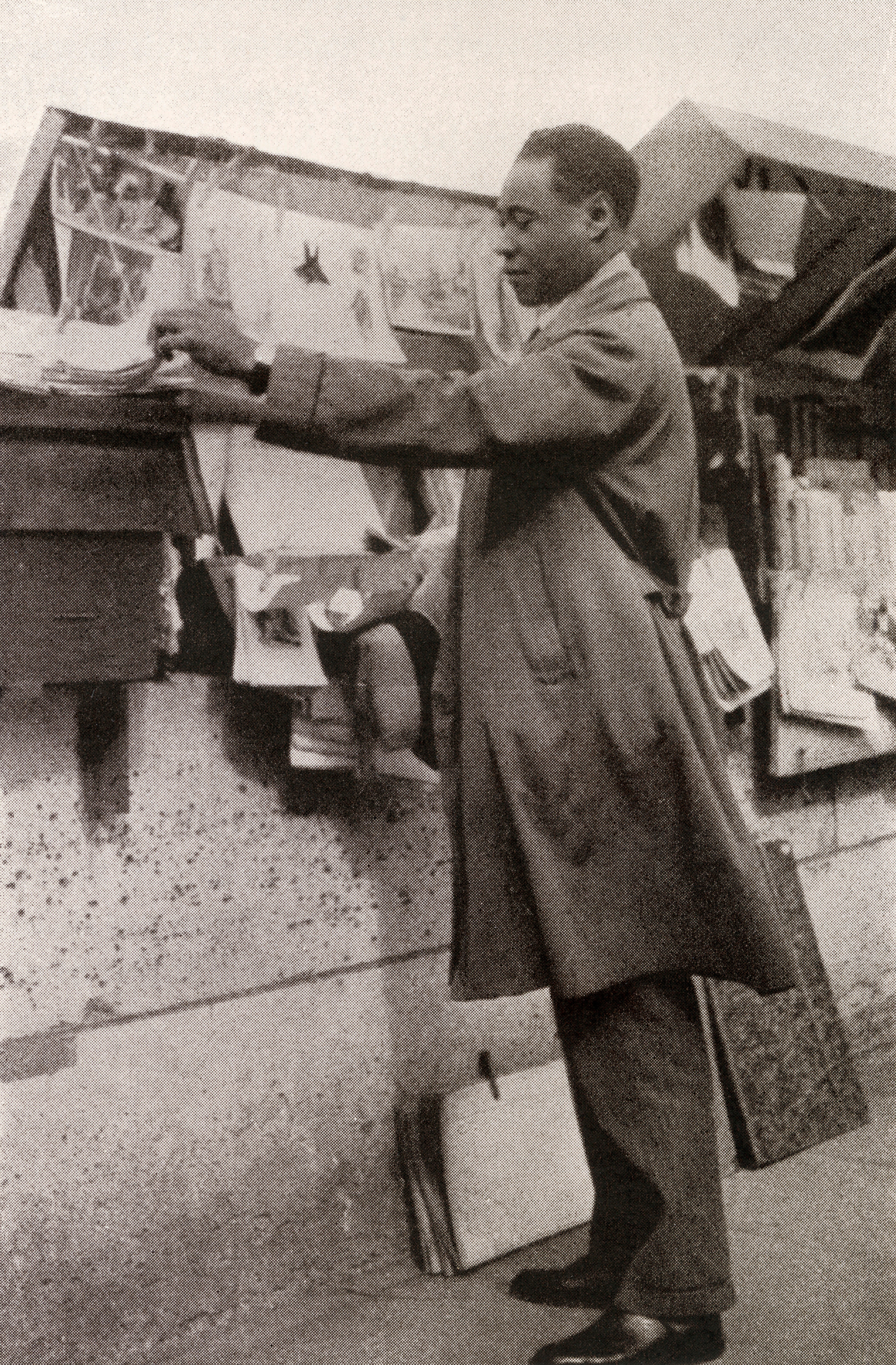 A antheral   successful  a trench overgarment  browsing a sidewalk bookstall, surrounded by books and papers
