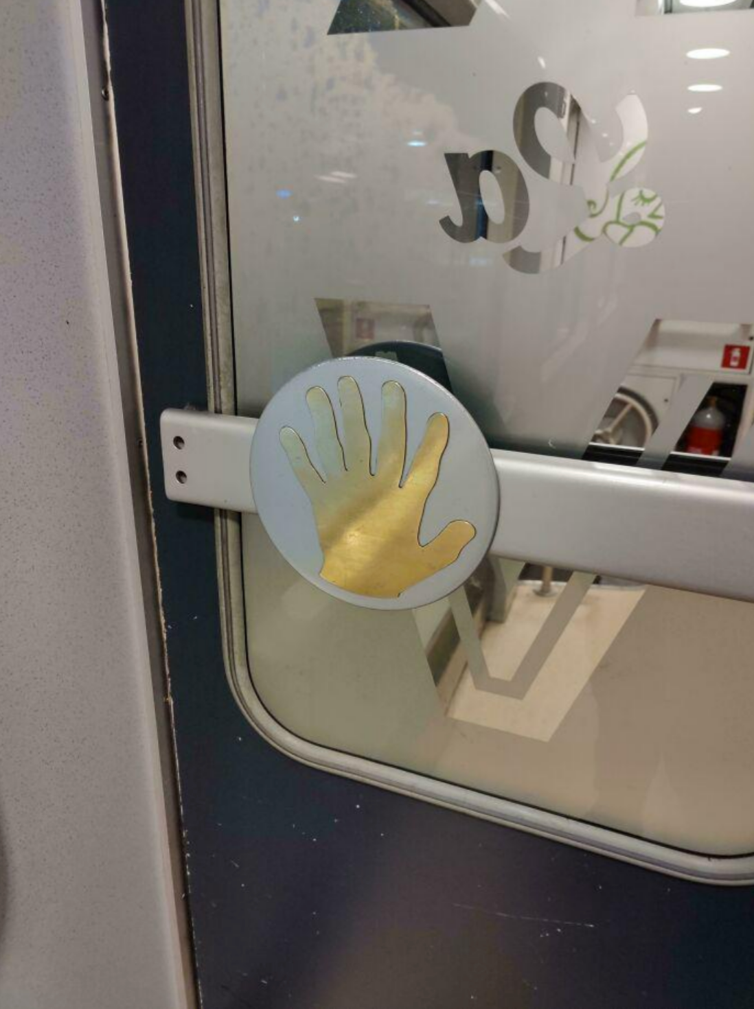 Handprint stickers with six fingers on a train door, possibly indicating a push button for opening the door