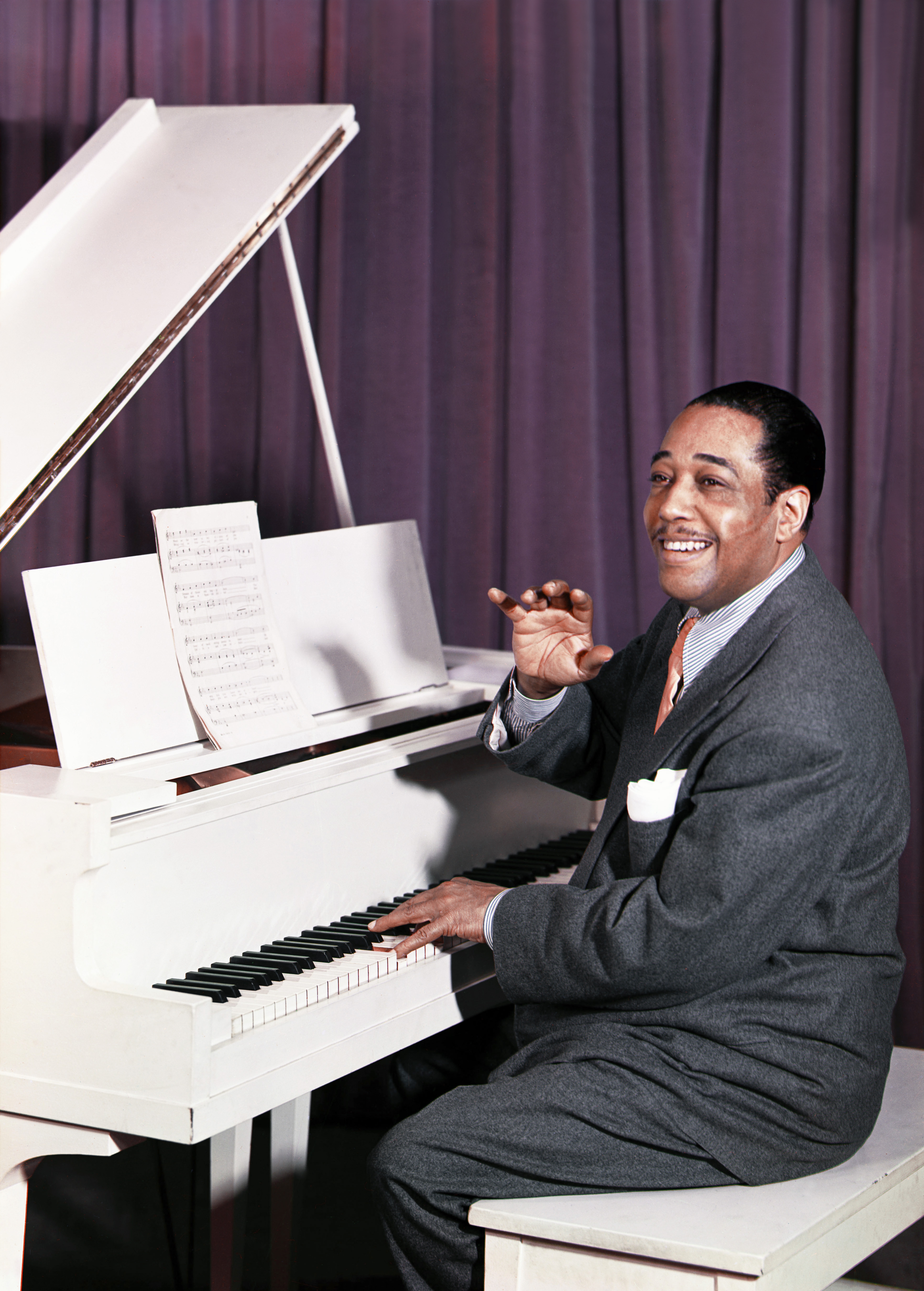 Musician playing a expansive  soft  with expanse  music, smiling portion    gesturing with his hand, wearing a suit