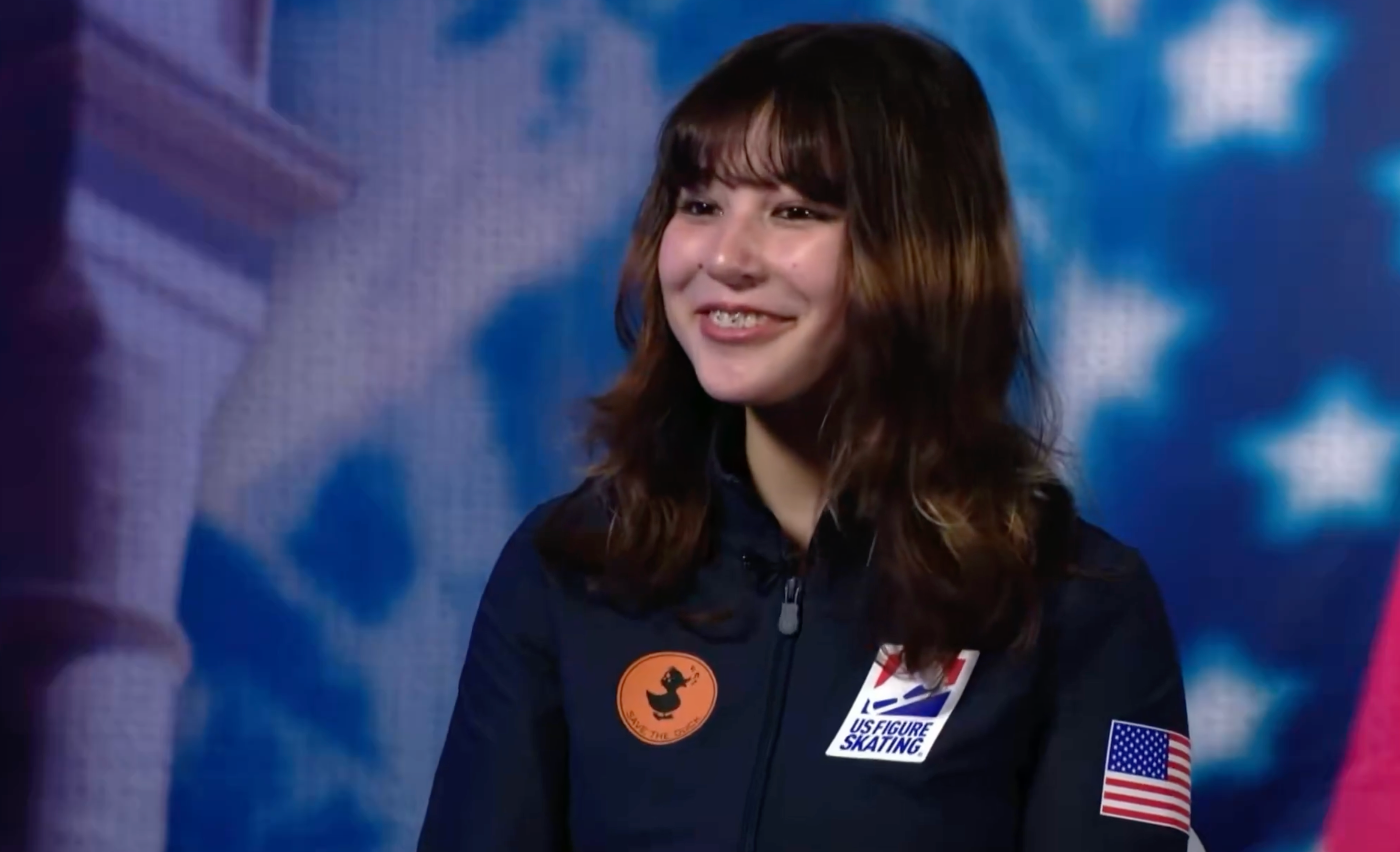 Person smiling, wearing a Team USA skating overgarment   with logos, appears successful  a property   oregon  interrogation  setting