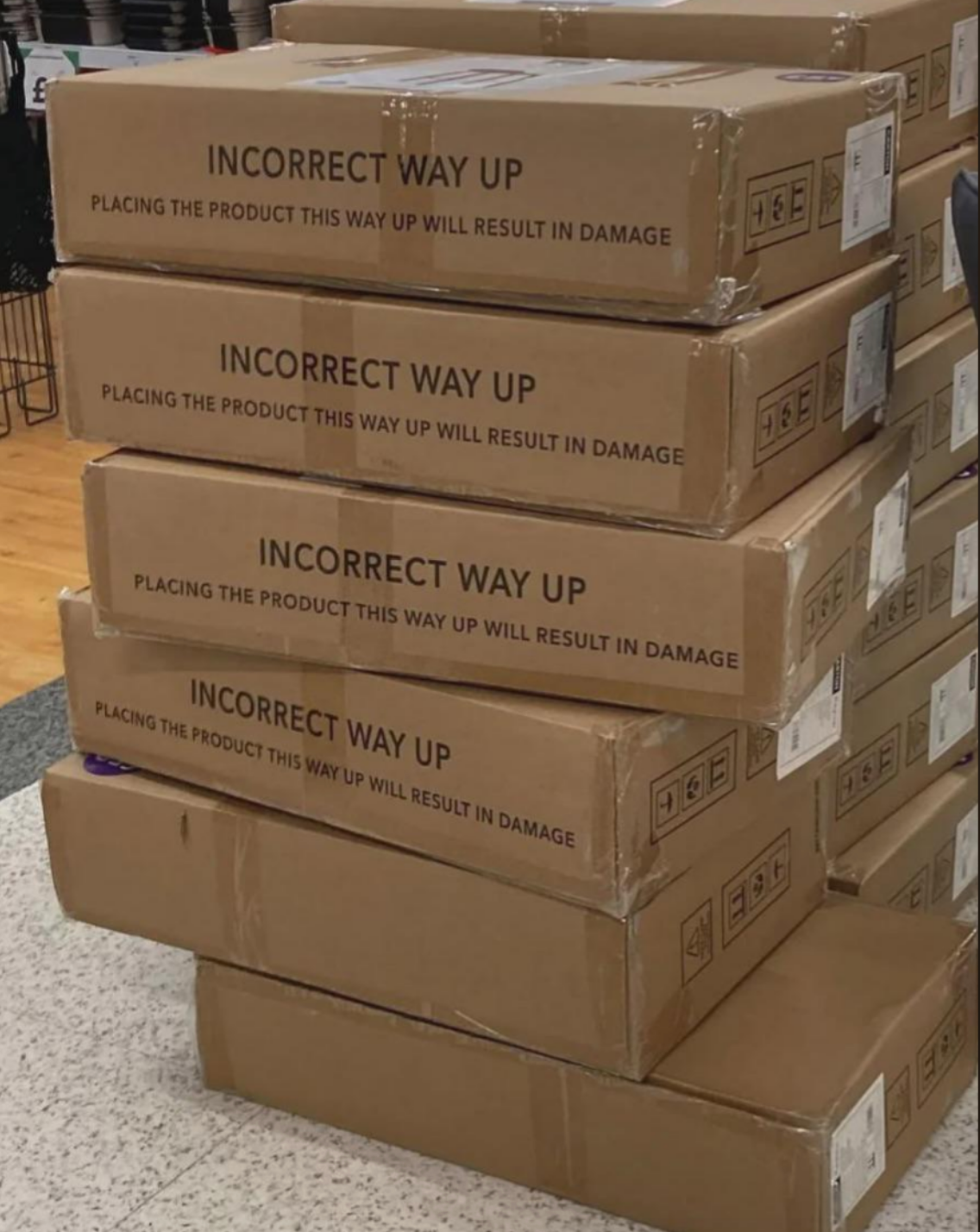 Stack of boxes labeled "Incorrect Way Up" with warnings about potential damage