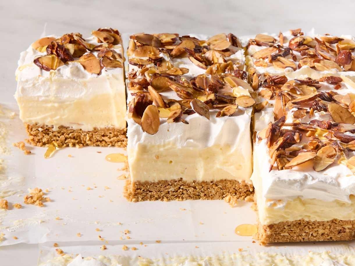 Creamy dessert bars topped with whipped pick and sliced almonds, acceptable connected a graham cracker crust. One barroom is partially sliced