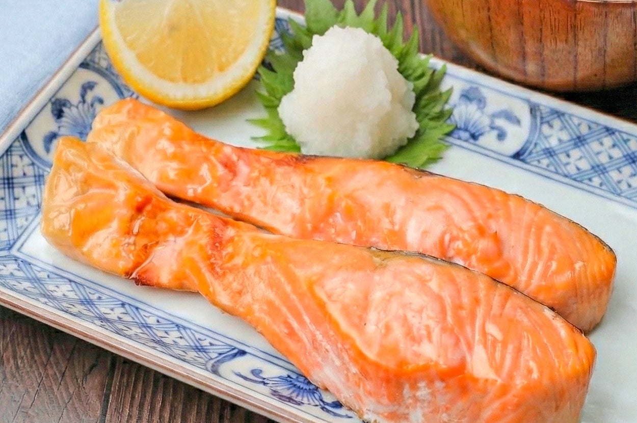 和風の皿に盛られた焼き鮭の切り身2枚、大根おろし、レモン、味噌汁が添えられています。