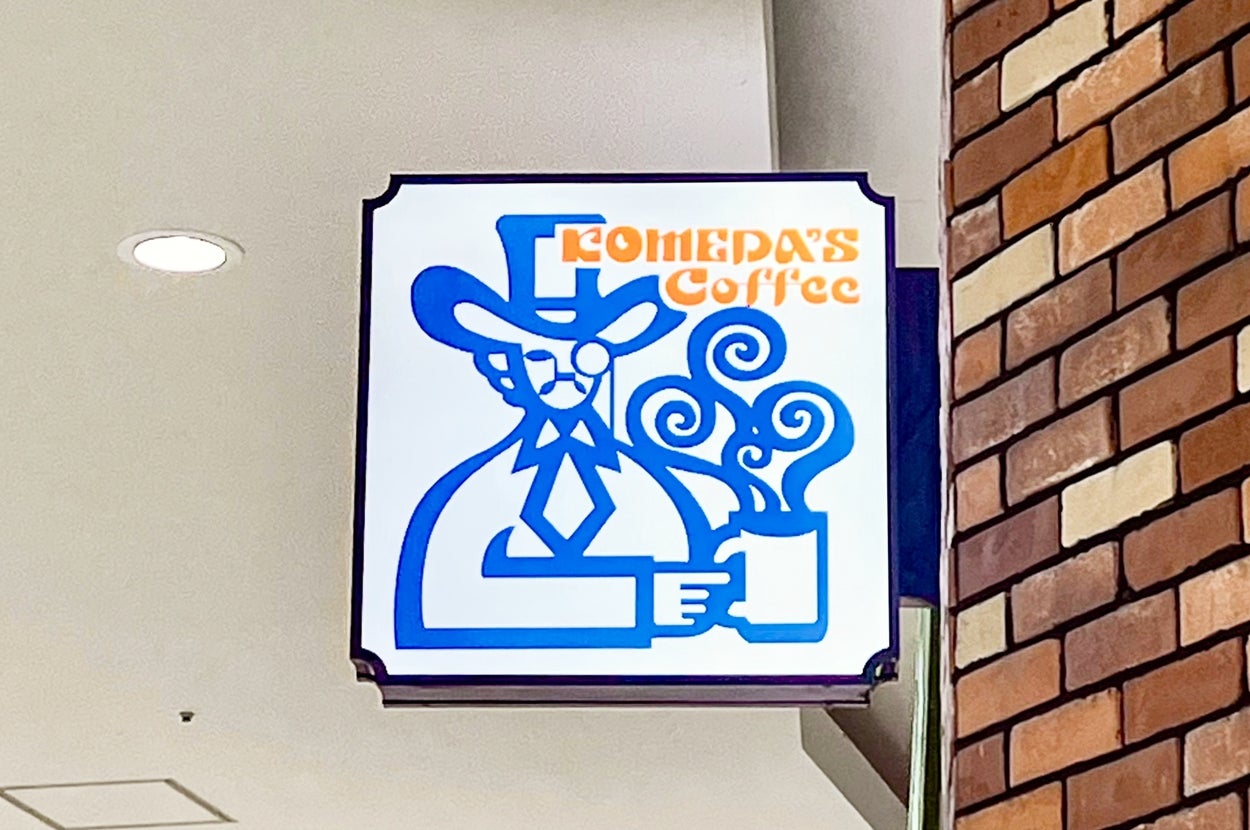 喫茶店「コメダ珈琲店」の看板が表示されています。帽子をかぶった人物がカップを持っています。