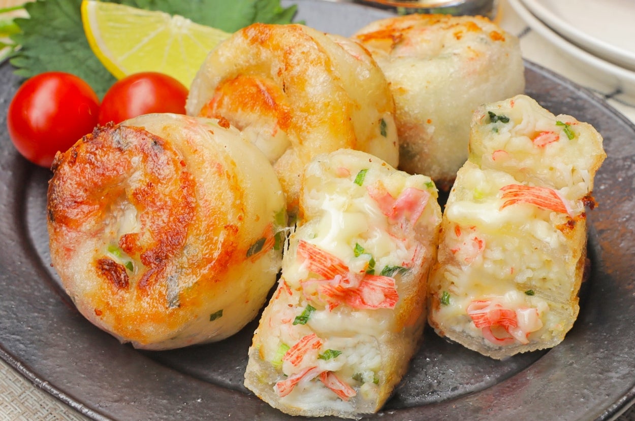 お皿に盛られた焼き餃子。内部にはカニや野菜の具が見え、横にレモンとプチトマトが添えられている。