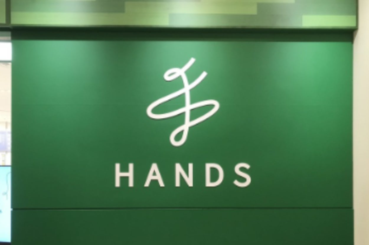 緑の背景に白字で「HANDS」と書かれた看板。上部に店のロゴが配置されている。