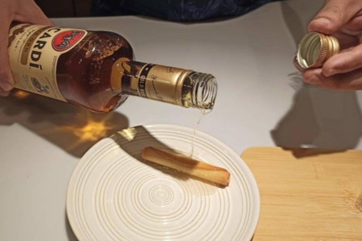 ヨックモックの「シガール」にボトルからラム酒を注いでいる様子。テーブルには木製のボードも見える。