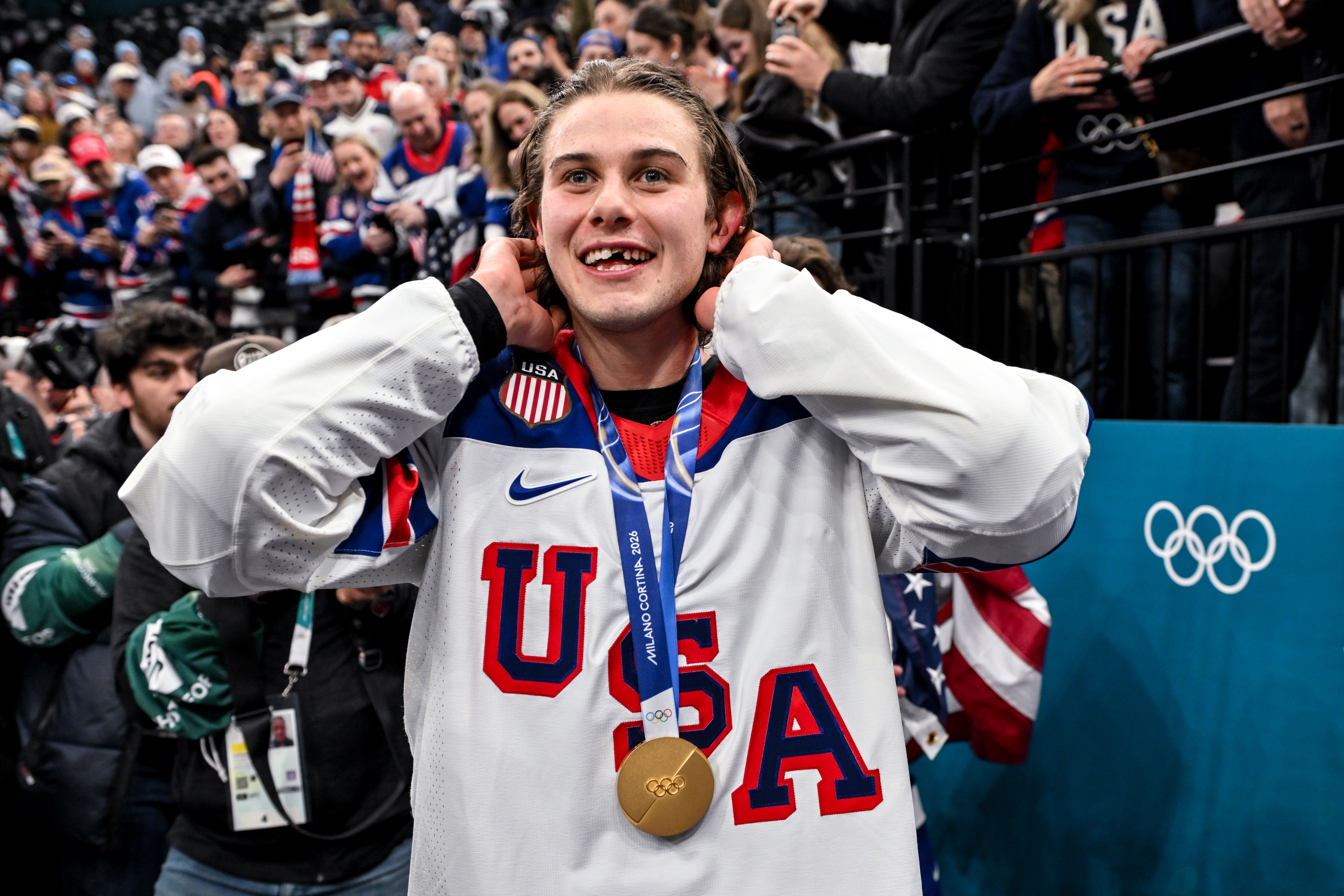 Athlete successful  Team USA hockey jersey celebrates with Olympic golden  medal, surrounded by cheering crowd