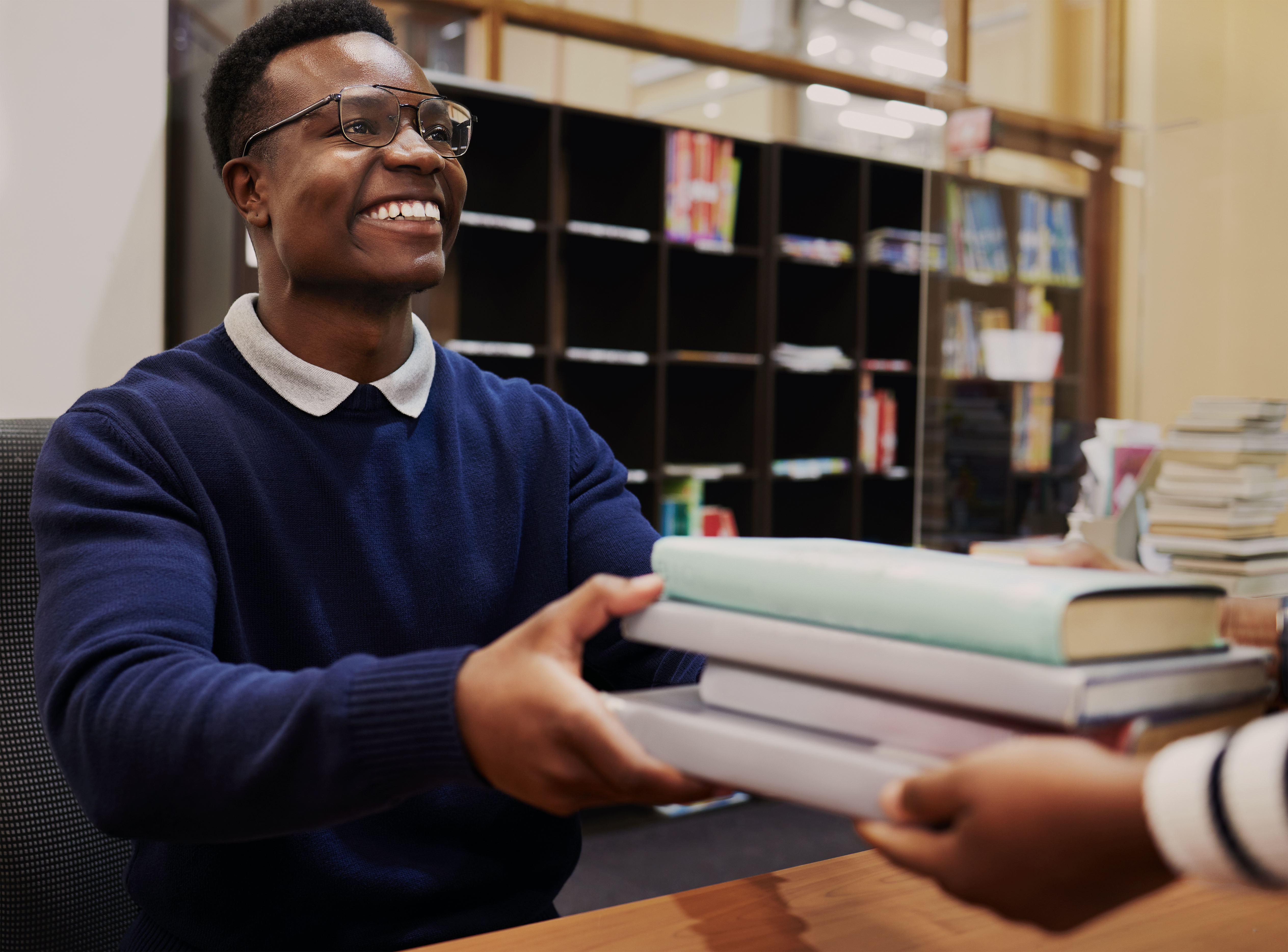 Librarian smiling and handing books to someone