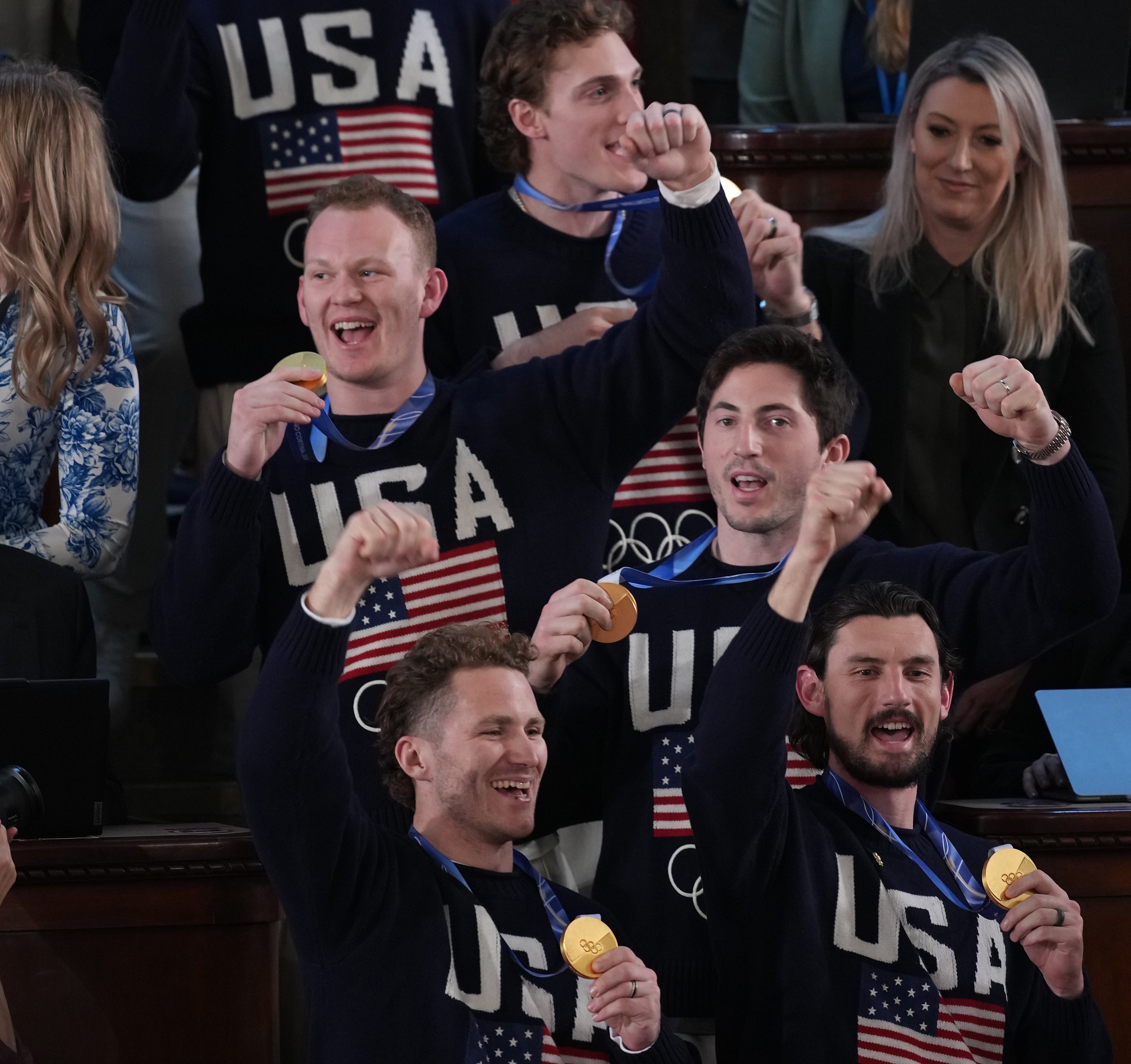 Atletiske lagmedlemmer som har på seg "USA" gensere feirer med medaljer i et overfylt lokale