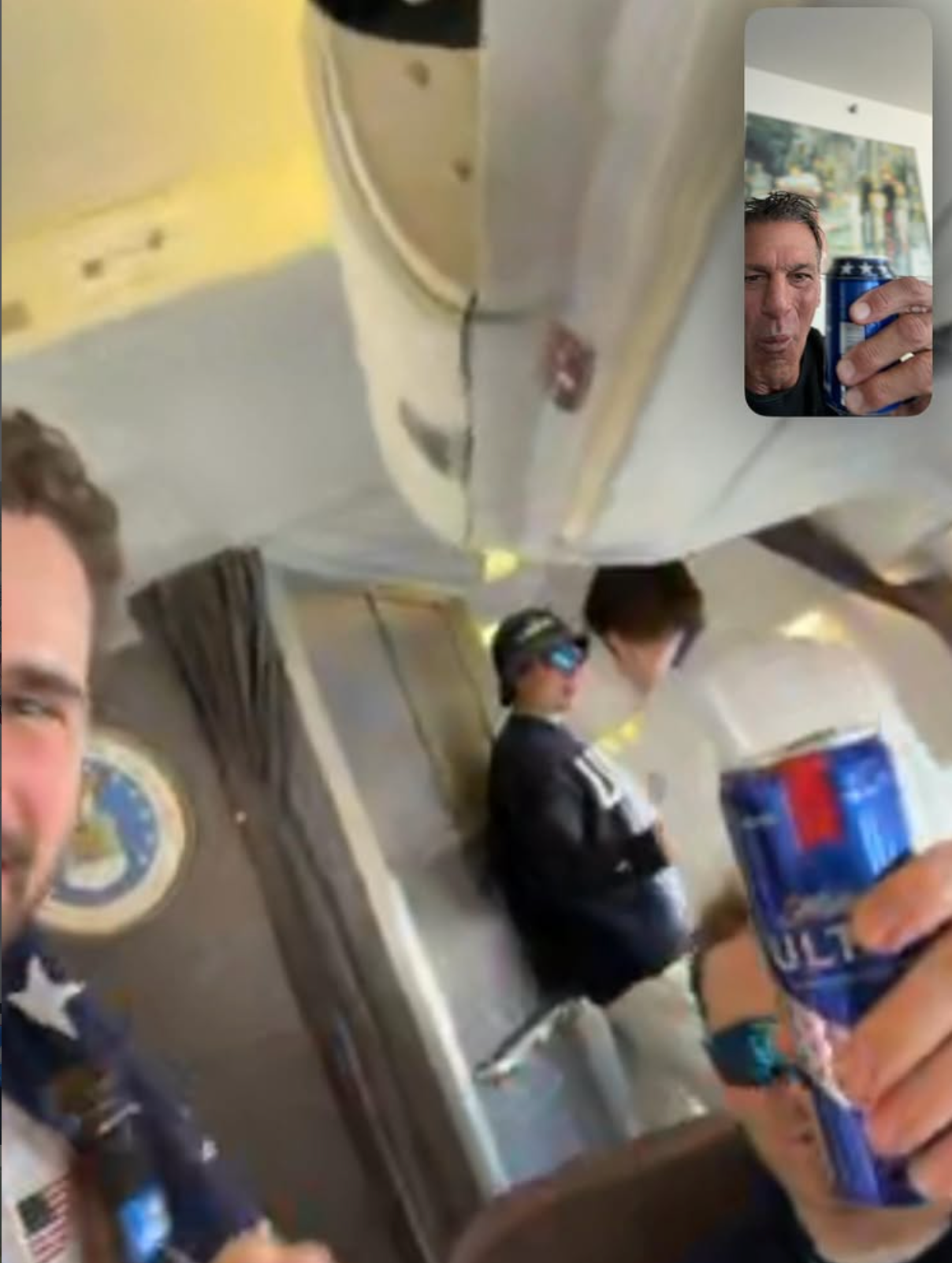 Folk på et fly holder drinker, én person er i en videosamtale og deler en skål. Uformell atmosfære