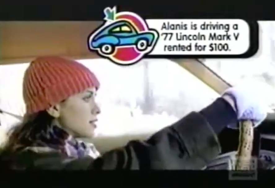 Person successful a car, wearing a knit hat, with substance stating, "Alanis is driving a '77 Lincoln Mark V rented for $100."