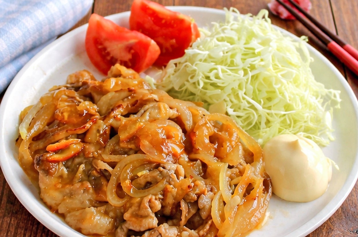 キャベツとトマト、焼肉と玉ねぎの炒め物が盛られた食事が白い皿に載っている。