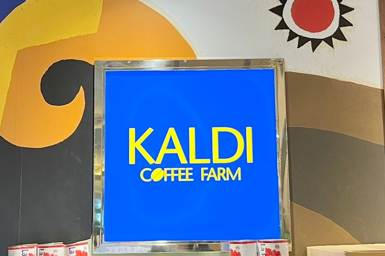 店内の壁にカラフルなアートと積み上げられた商品の箱が置かれている「カルディコーヒーファーム」の看板。