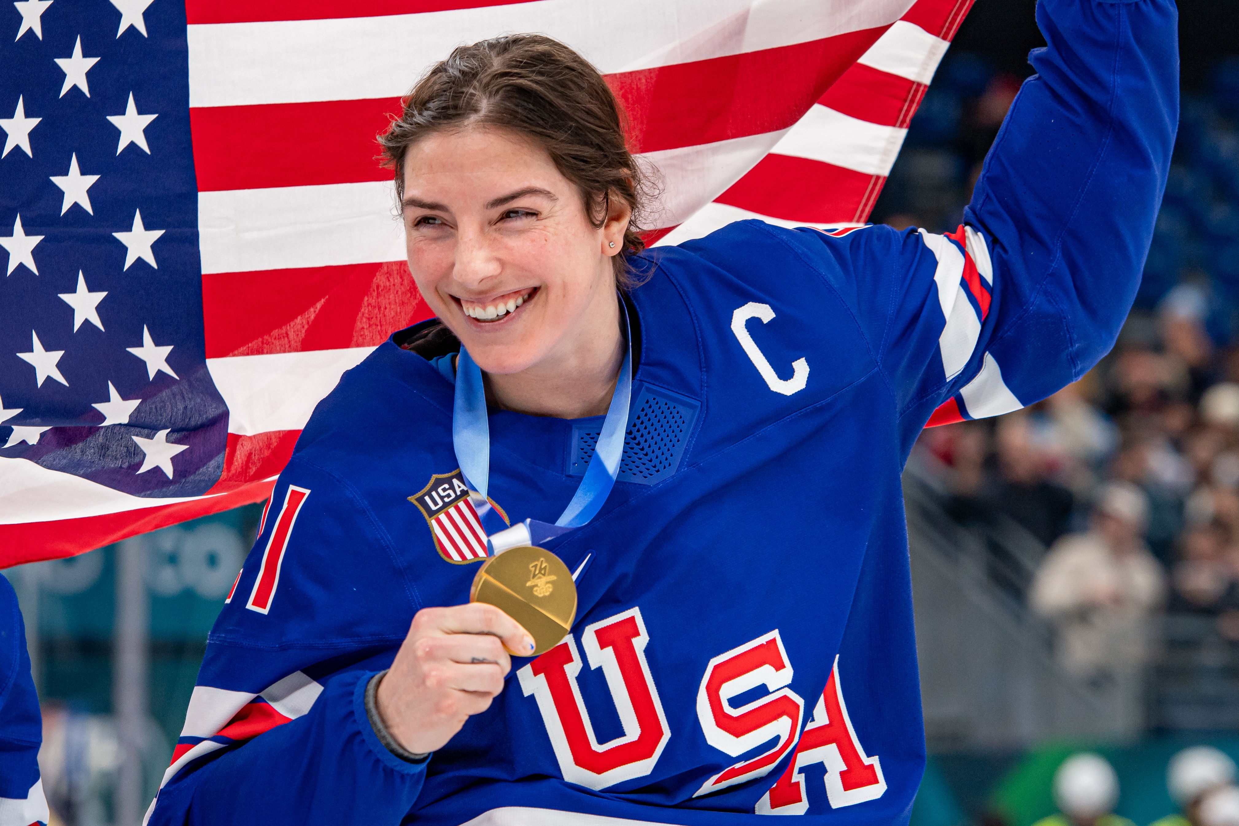 Hilary Knight holding a gold medal and an American flag, smiling