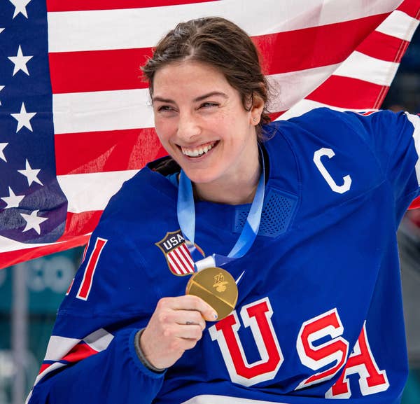 Hilary Knight holding a gold medal and an American flag, smiling