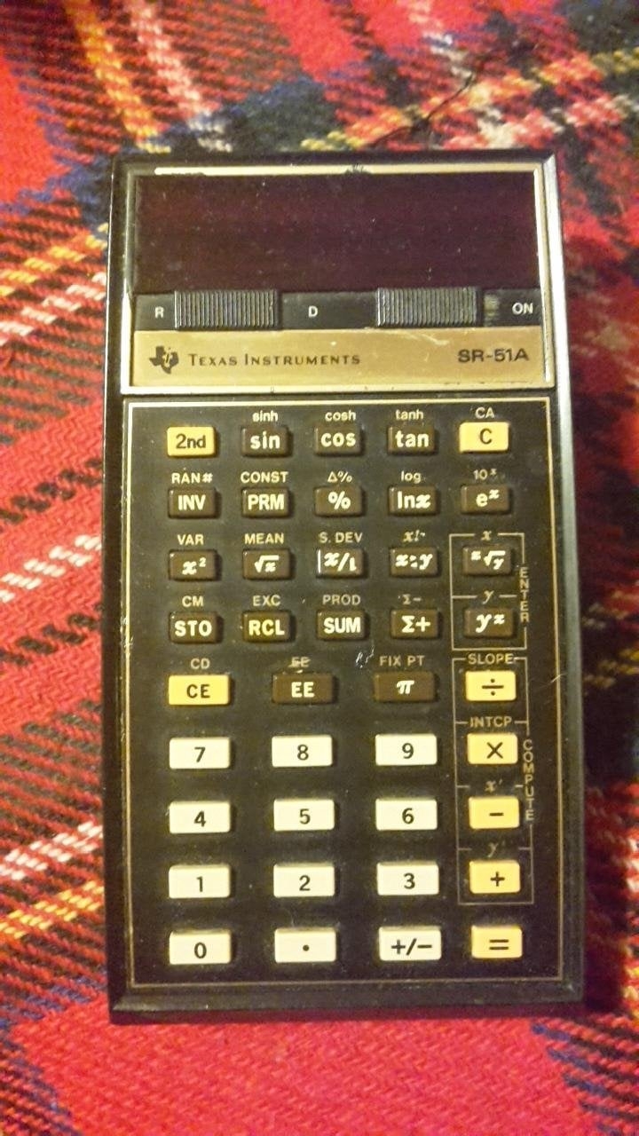A vintage Texas Instruments SR-51A technological  calculator with a assortment  of relation  buttons, placed connected  a plaid cloth  surface
