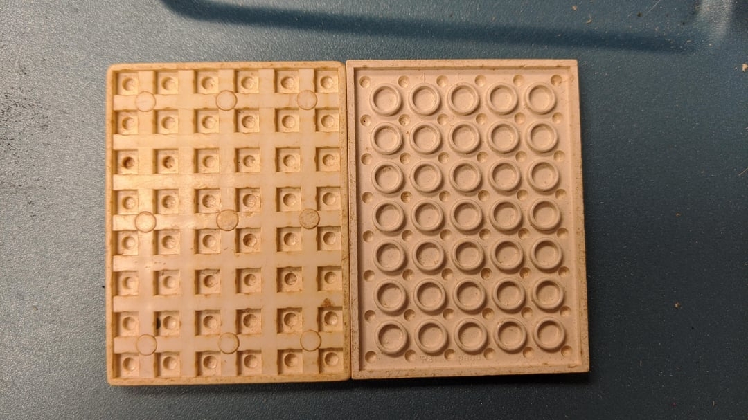 Close-up of 2  vintage LEGO baseplates, 1  with a grid of squares and the different   with a grid of circles, connected  a level  surface