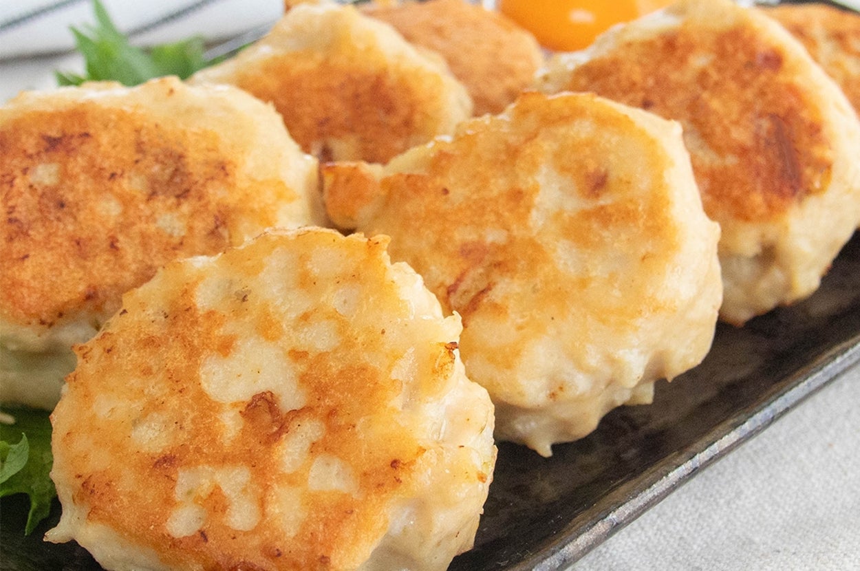 玉ねぎ入りゆずコショウ鶏つくねが皿に盛られている。卵黄が添えられている。