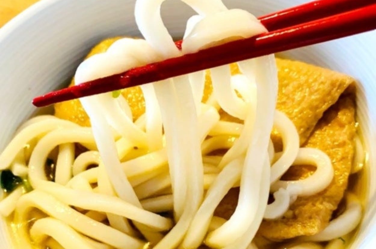 つるとんたんの「きつねのおうどん」の麺を箸で持ち上げている様子。