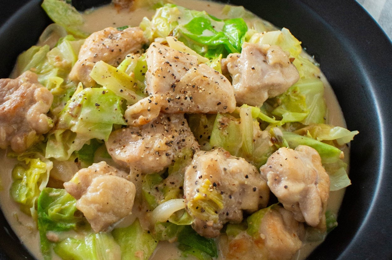 鍋に盛られたチキンとキャベツのクリーム煮。後ろに木製のスプーンと皿。