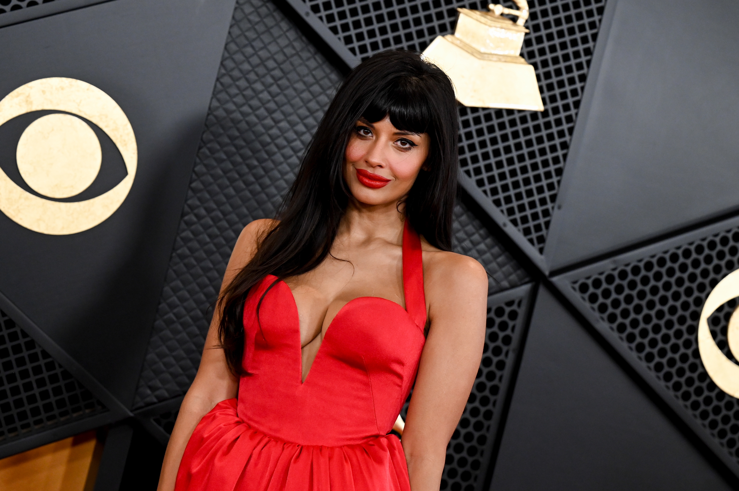 Jameela Jamil connected  the reddish  carpet wearing a bold strapless gown with a plunging neckline, lasting  successful  beforehand   of a Grammys backdrop with logos