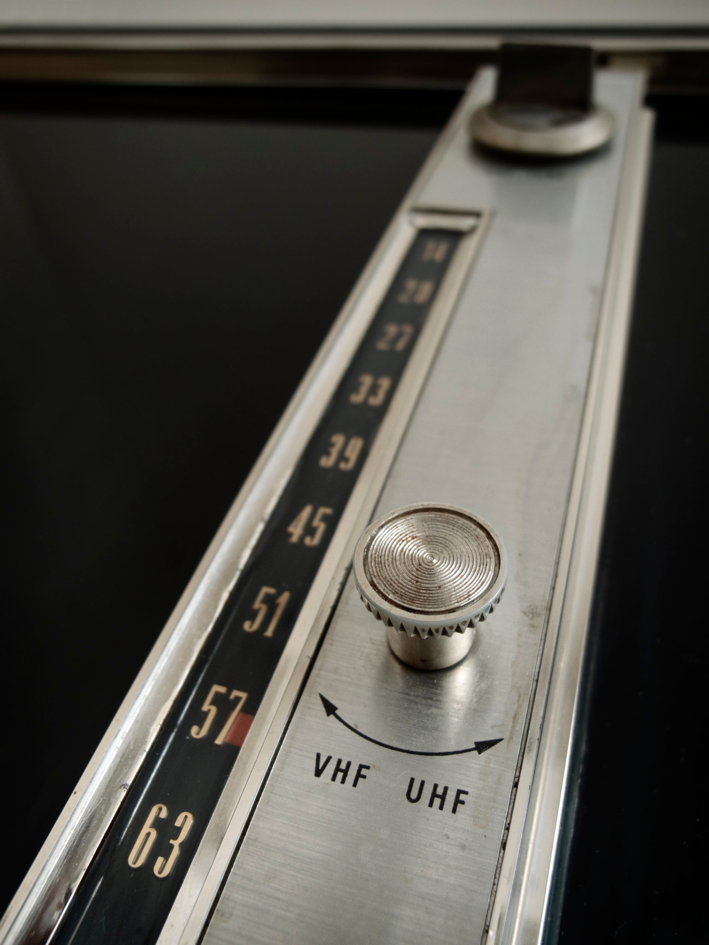 Close-up of a vintage TV dial, showing a VHF and UHF transmission  enactment    knob, indicating an old-fashioned tv  power  system