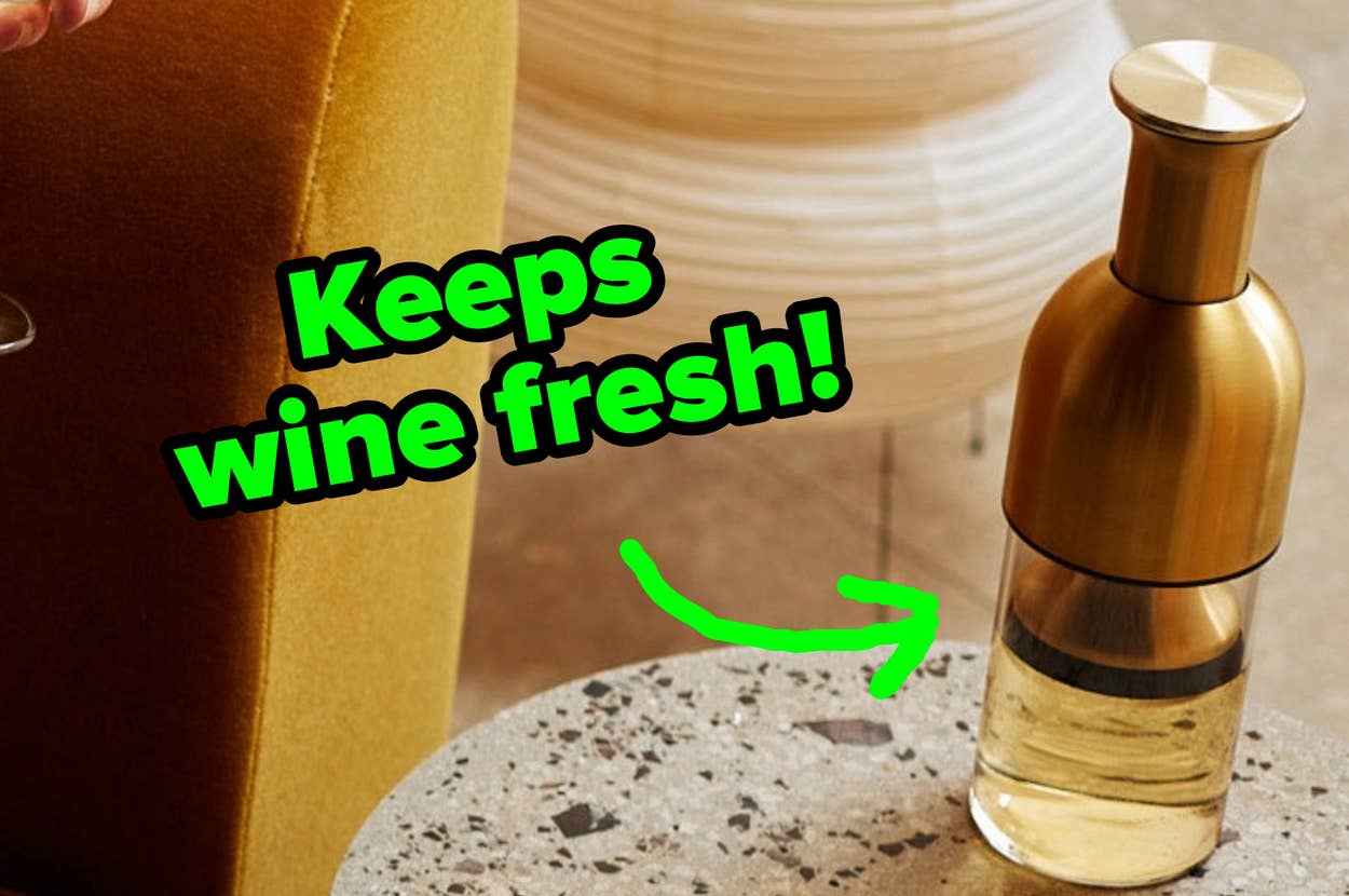 Person reading on a sofa with a wine glass; a modern side table with a carafe and lamp is nearby, suggesting a stylish home setting