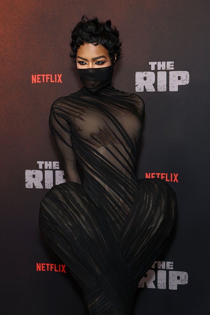 Person successful a form-fitting, sheer achromatic outfit with a look disguise connected a reddish carpet, lasting successful beforehand of a Netflix backdrop