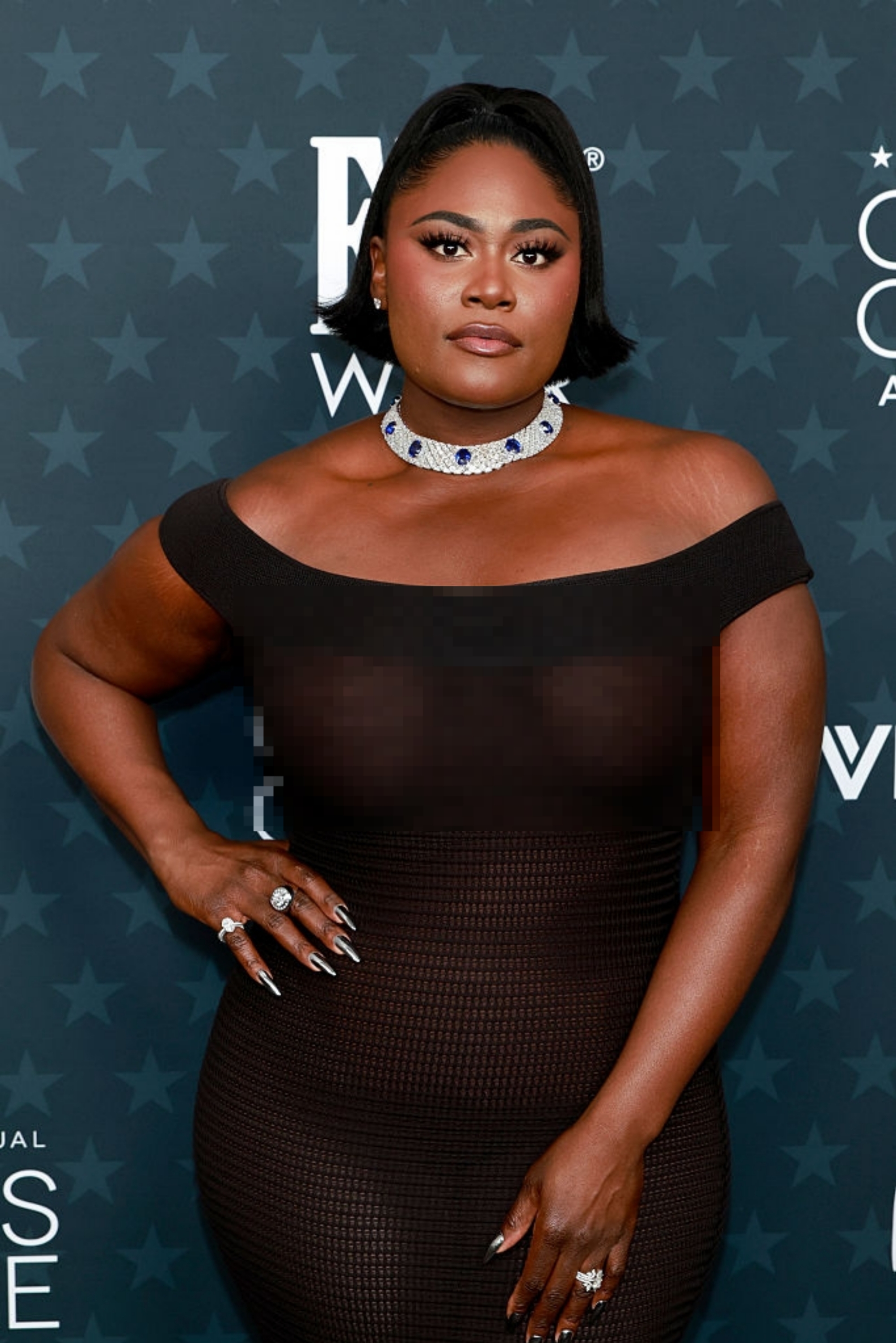 Person connected reddish carpet successful form-fitting, off-the-shoulder formal with patterned choker necklace, posing confidently