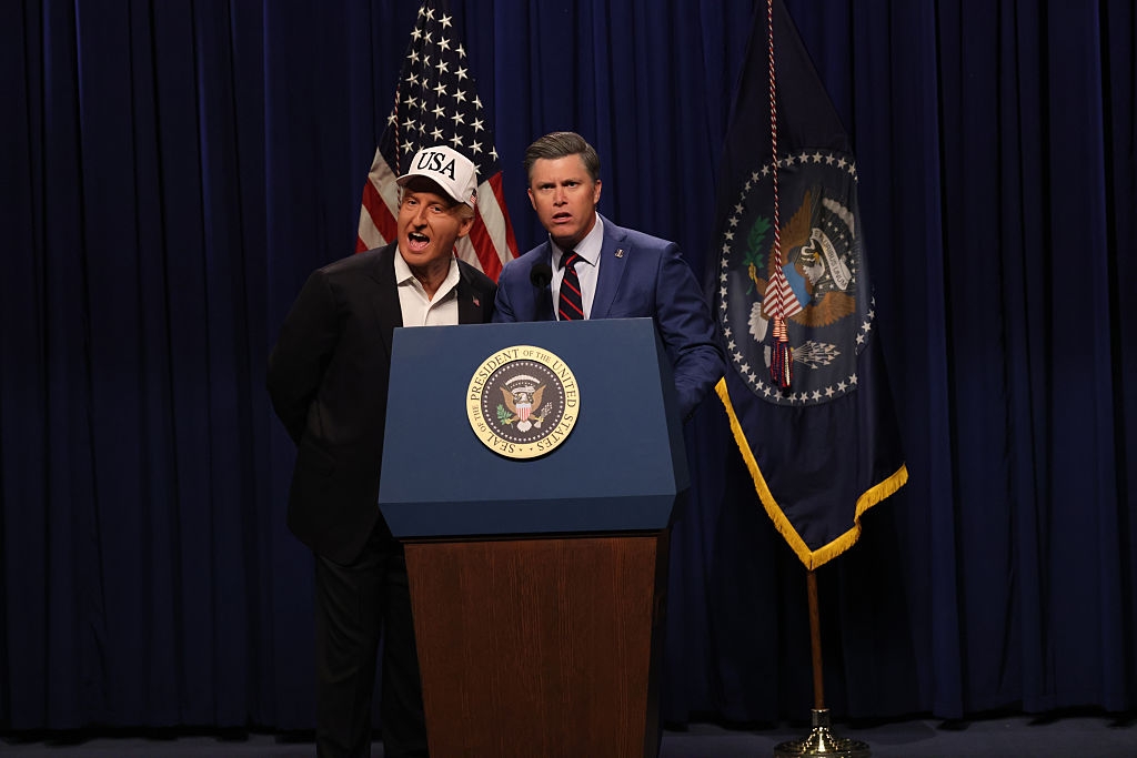 Two actors impersonating governmental figures basal astatine a podium labeled with a statesmanlike seal, with USA and flags successful the background