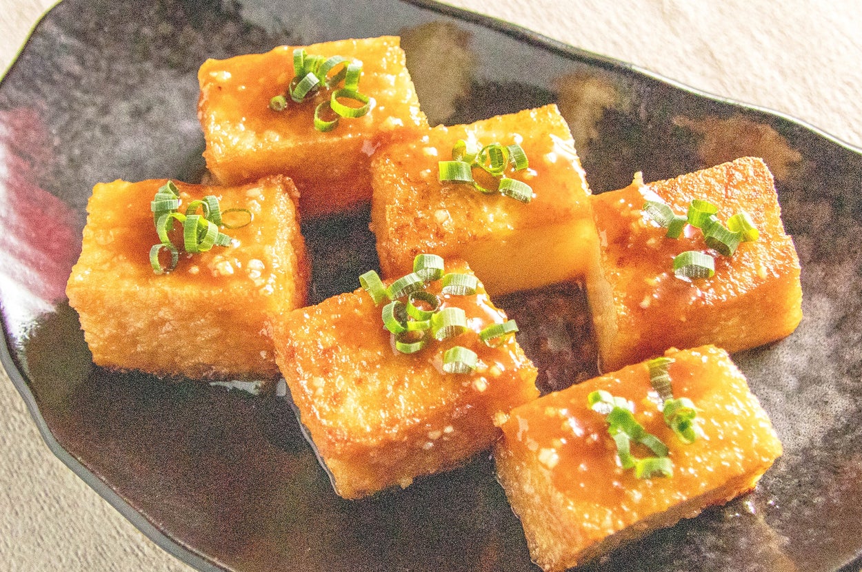 豆腐の揚げ出し。カリッと揚げた豆腐に、タレとネギがかかっている和風料理の一皿。