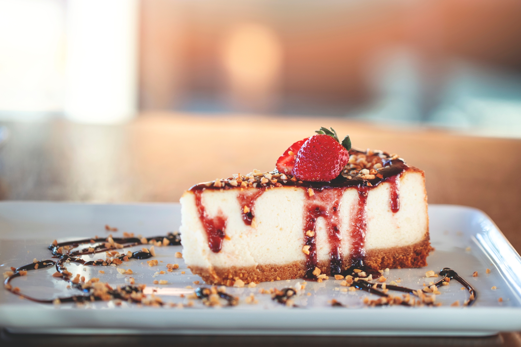 Cheesecake portion topped with strawberry, nuts, and drizzled cocoa connected a achromatic plate