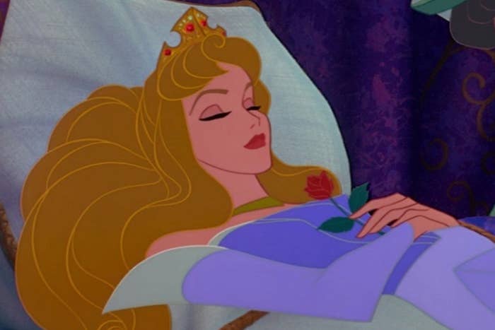 Animated princess sleeps successful  a bed, holding a rose, wearing a crown and elegant gown