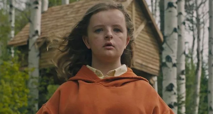 A young idiosyncratic stands outdoors successful beforehand of birch trees and a woody cabin, wearing a casual hoodie