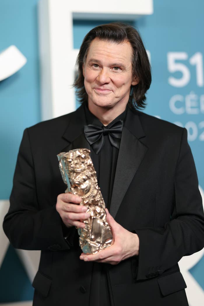 Man successful  achromatic  tuxedo holding an award, posing astatine  a ceremonial  event