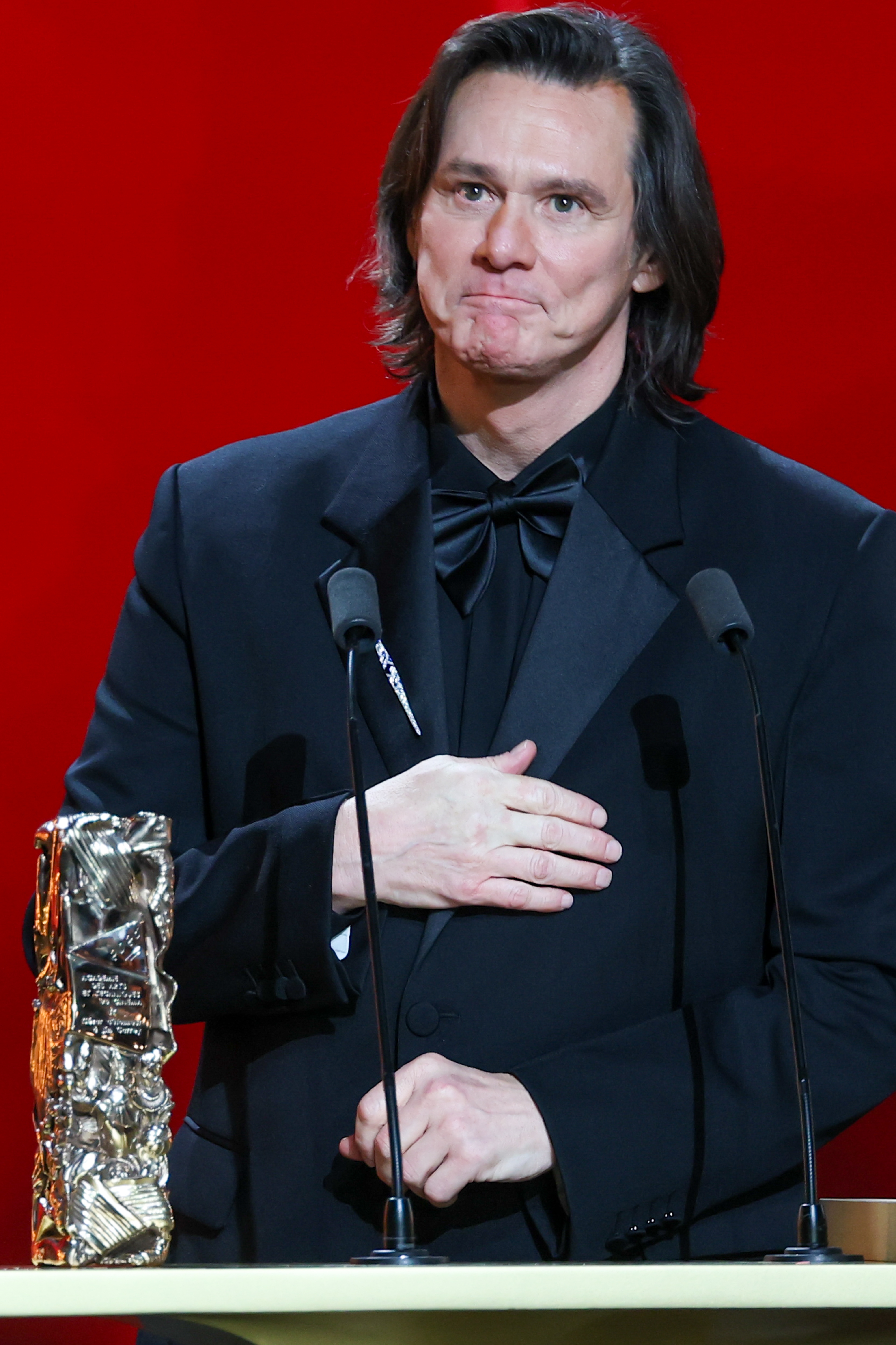 Actor successful a ceremonial suit and bow necktie connected signifier making a heartfelt motion during an grant ceremony