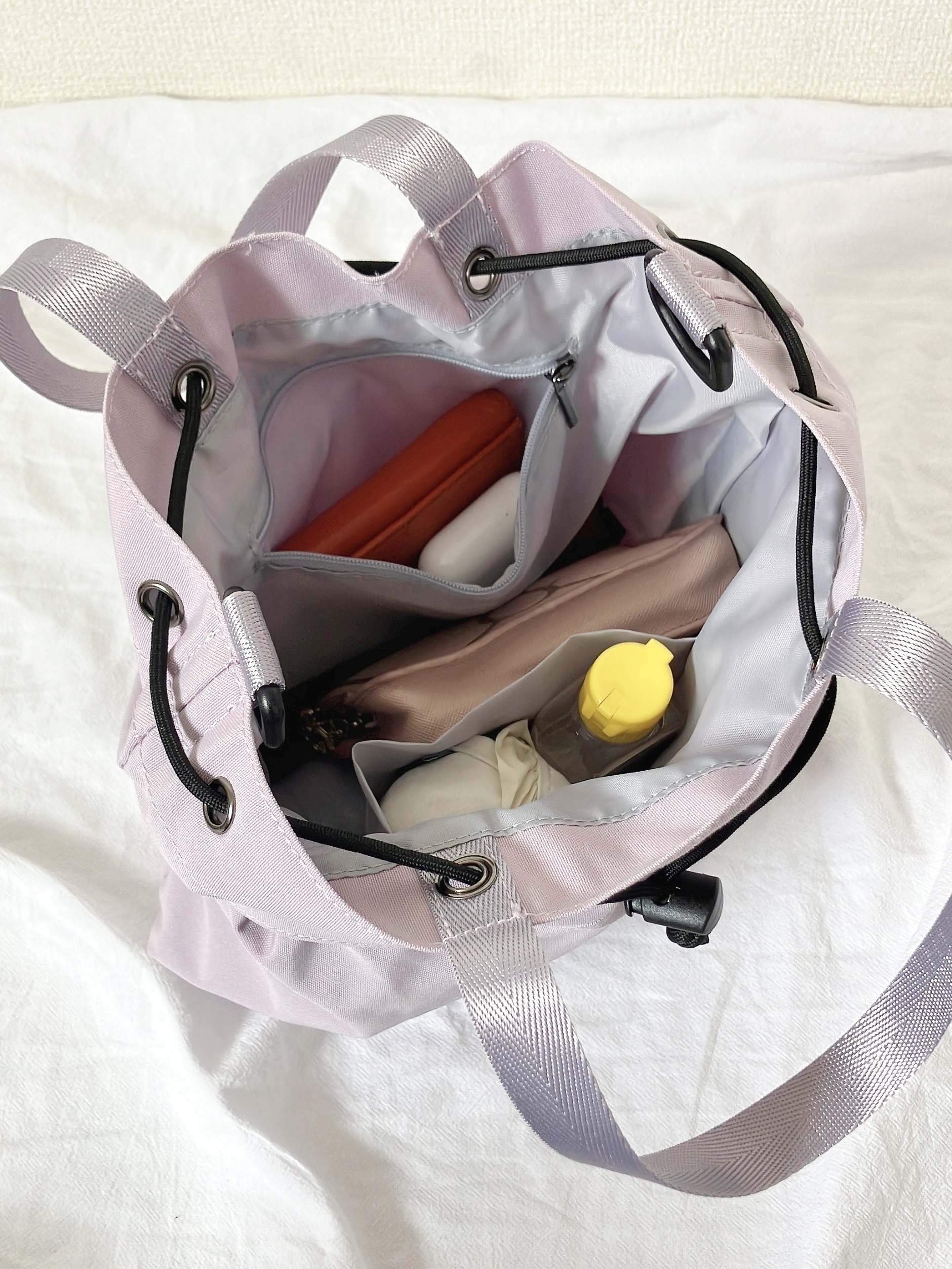 ワークマンの「撥水巾着ショルダーバッグ」バッグの中には財布、ペンケース、折りたたみ傘、水筒、ハンドクリームが整然と収納されている。