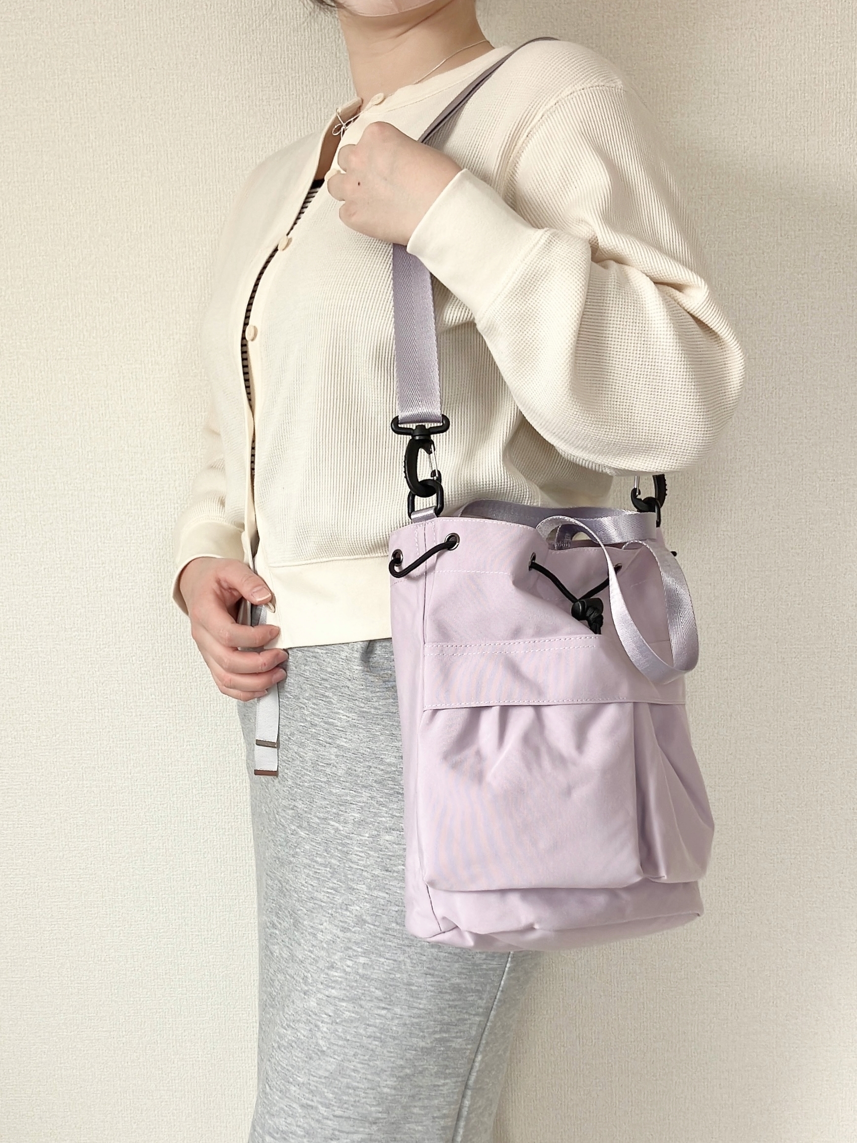 ワークマンの「撥水巾着ショルダーバッグ」女性がカジュアルな装いで肩にショルダーバッグを掛けている。バッグは小型でシンプルなデザイン。