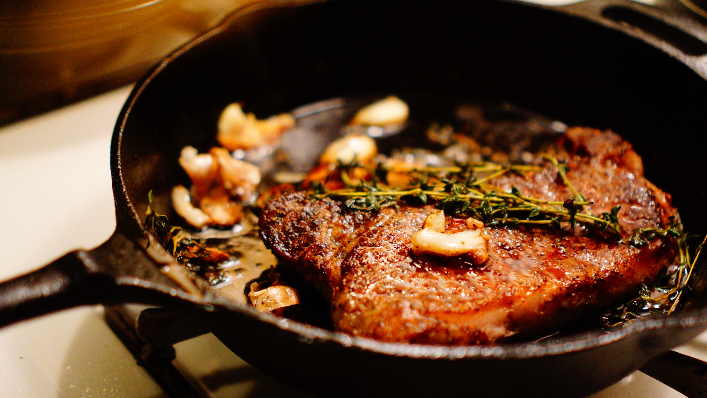 Steak cooking successful  a cast-iron skillet with ail  and herbs, creating a rich, savory dish