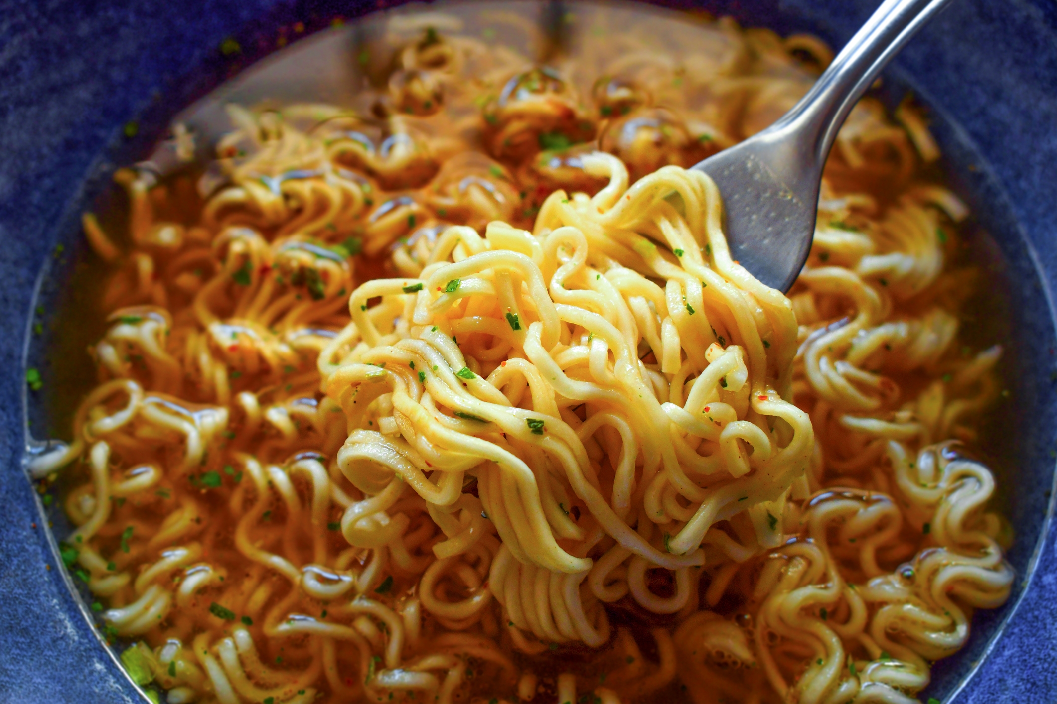 A vessel  of ramen noodles successful  a affluent  broth, with a fork lifting strands of noodles